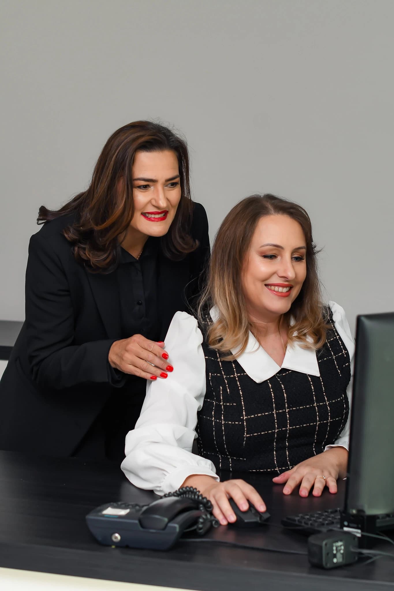 Duas integrantes da equipe Mercedes Imóveis trabalhando juntas no computador do escritório central em Itajaí