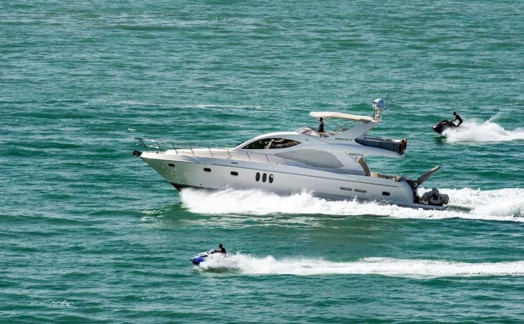 Homem usando colete salva-vidas pilotando um jet ski branco e roxo em alta velocidade, levantando grande borrifo de água.